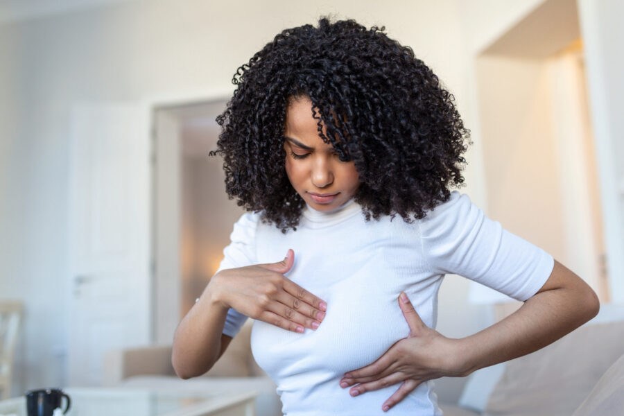 Young African American woman palpating her breast by herself that she concern about breast cancer. Healthcare and breast cancer concept
