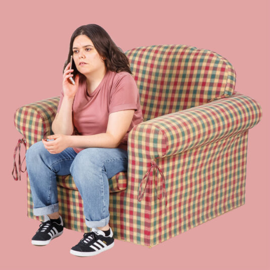 Woman using mobile phone sat on armchair