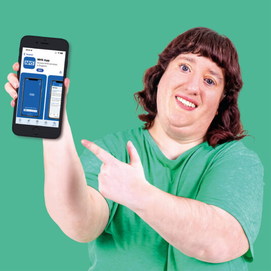 Woman holding mobile phone displaying the NHS mobile app
