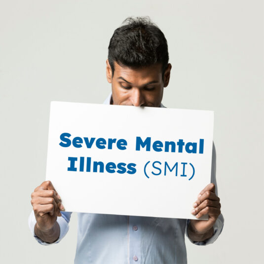 Man holding a card saying Serve Mental Illness (SMI)