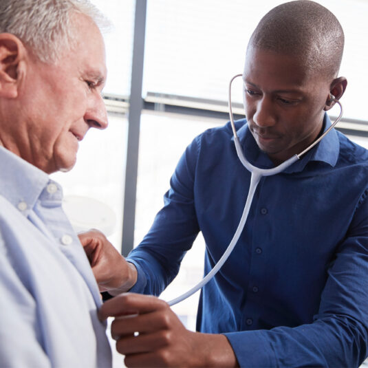 Male doctor checking a male patient with stethoscope