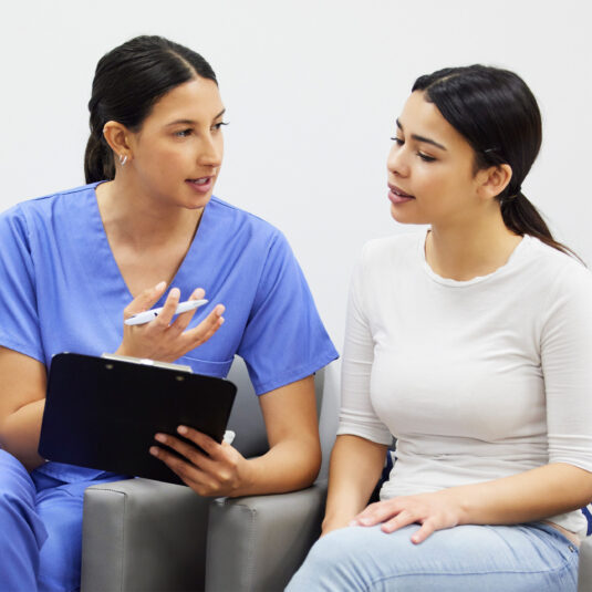 Nurse speaking to female patient with clipboard