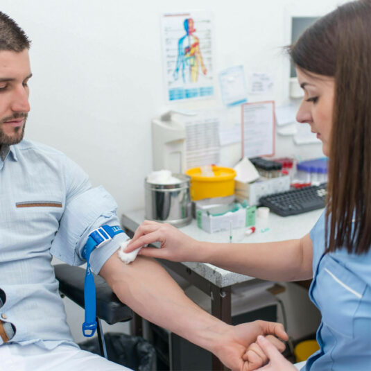 man having arm cleaned by female health worker before a blood test