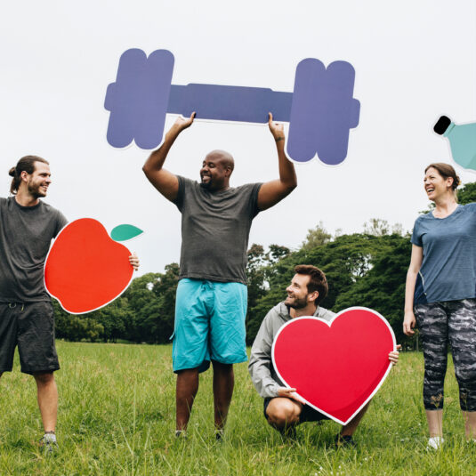 Four people outdoors holding colourful fitness and wellness icons