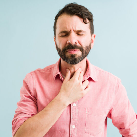 Man holding his throat in discomfort.