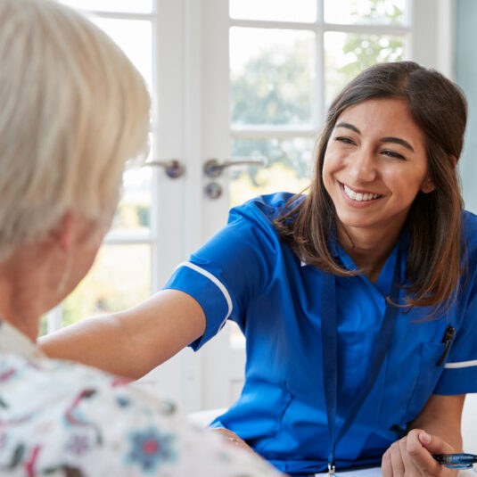 Nurse smiling and speaking with an elderly patient