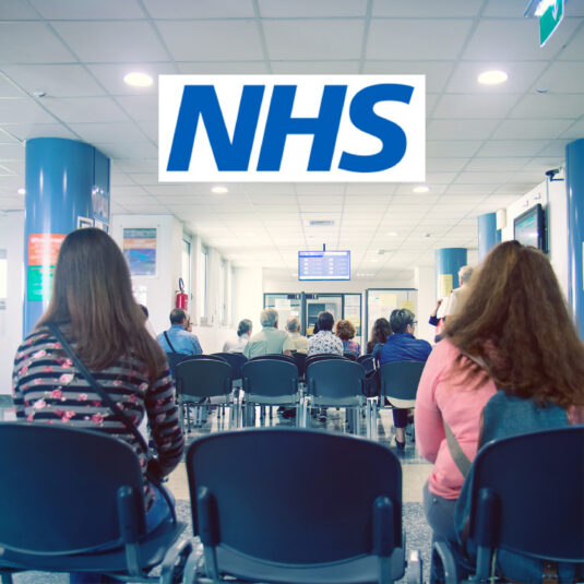 Patients waiting in an NHS hospital reception area.