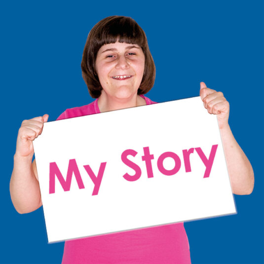 Person holding a sign reading “My Story.”