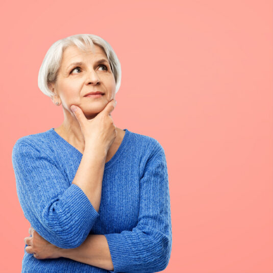 Older woman looking thoughtful with hand on chin.
