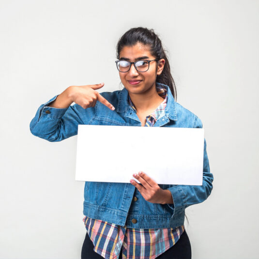 Person pointing to a blank sign, representing a message, opinion, or personal story.
