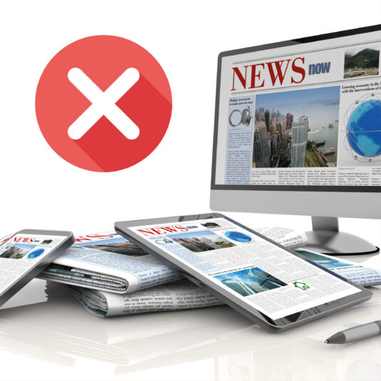 A red cross symbol beside digital news displayed on screens and newspapers