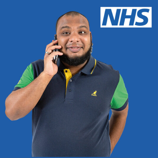 Man speaking on a mobile phone beside the NHS logo.