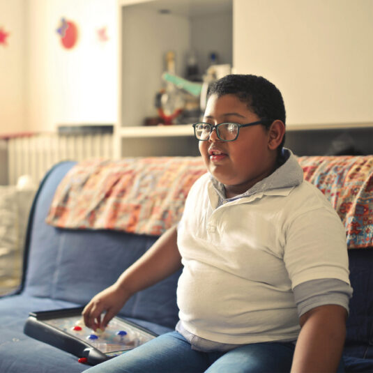 Young boy sitting on a sofa at home using an accessible communication device.