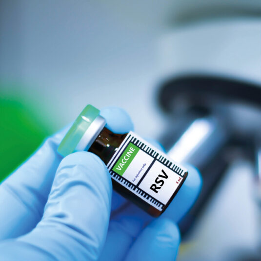 Close-up of a healthcare worker holding a vial labelled RSV vaccine.