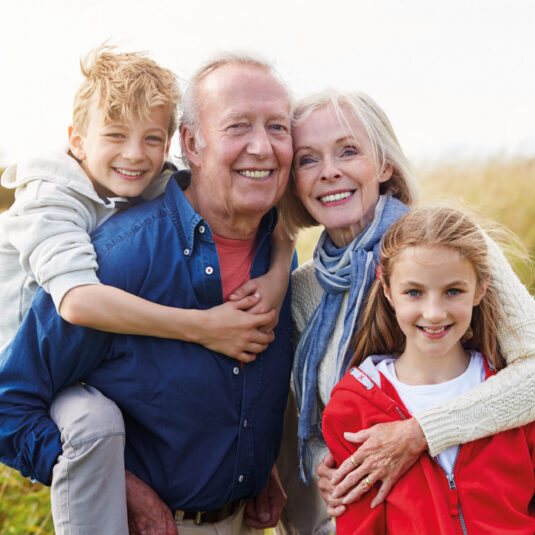 Grandparents posing outdoors with two smiling children