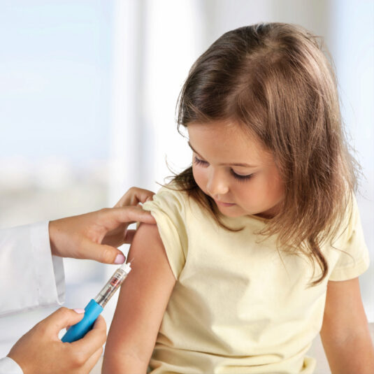 Healthcare professional preparing to give a vaccination or injection to a young girl.