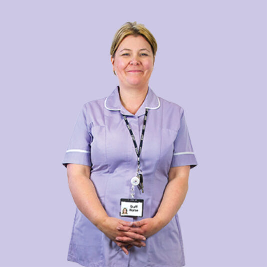 Nurse in a purple uniform standing with an NHS identification badge against a plain background.