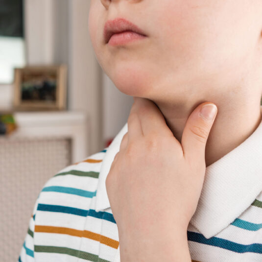 Child touching the neck/throat area, indicating a sore throat or swollen glands.
