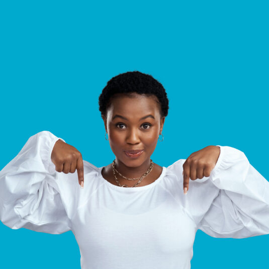 Woman pointing downward with both hands, commonly used to direct attention to information, links, or guidance below.