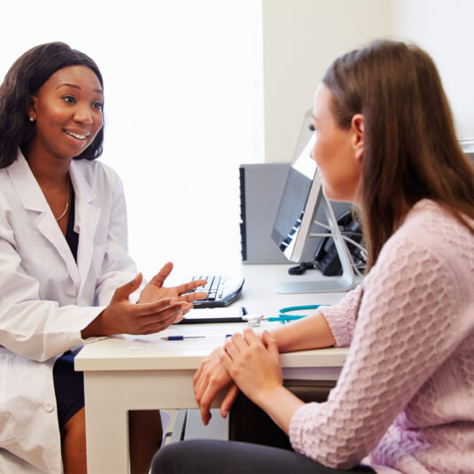 Doctor consulting with a patient in a medical office, showing healthcare advice, support, or assessment.