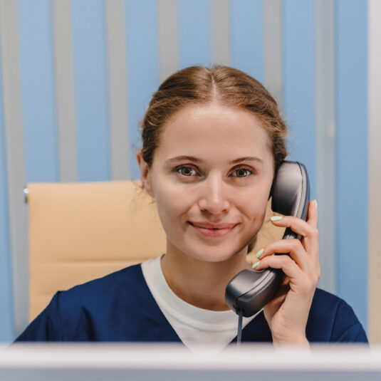 Healthcare worker speaking on the phone, representing helpline, appointment booking, or medical advice services.