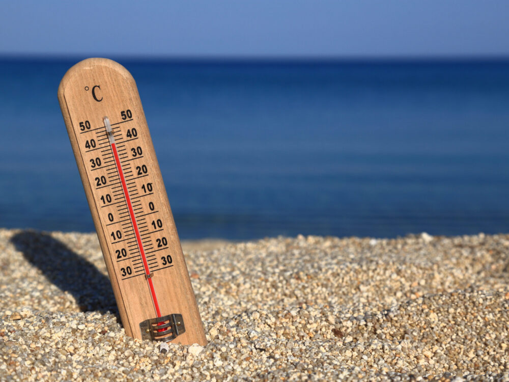 Thermometer on a beach shows high temperatures